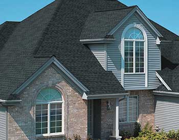 Front view of a typical mid-class home with dark gray GAF shingles on its roof